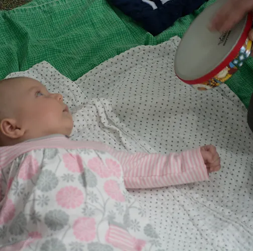 Baby looking at tambourine in baby music class