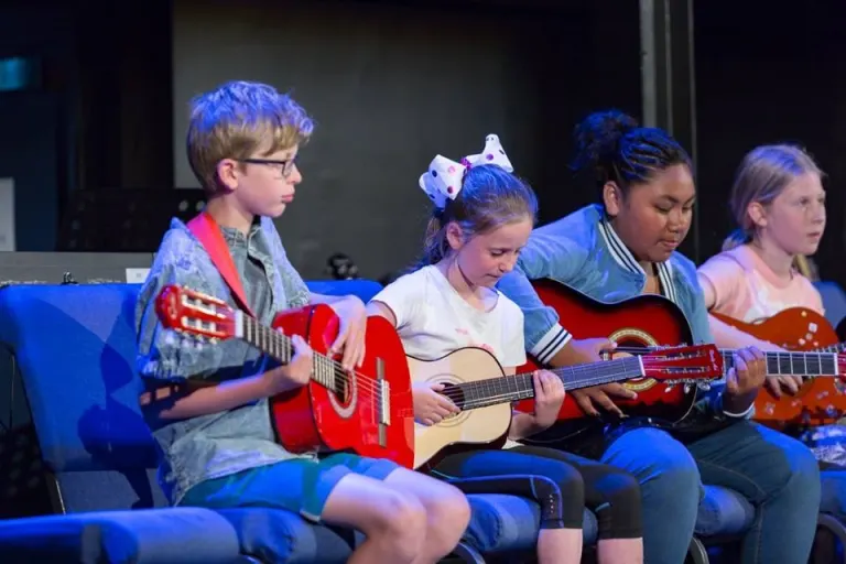 Kids playing guitars together in group music program