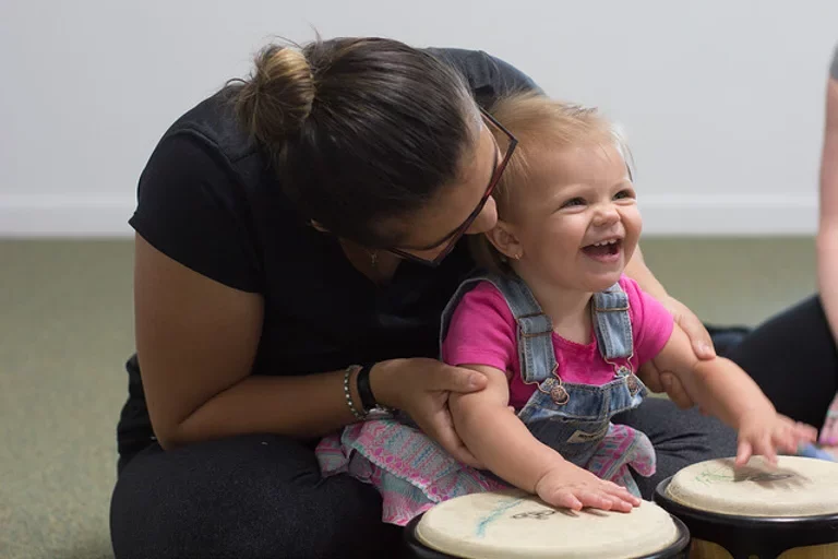 Mom and laughing toddler playing bongo drums