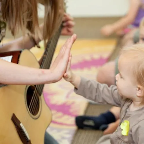 Toddler high fiving guitar teacher close up