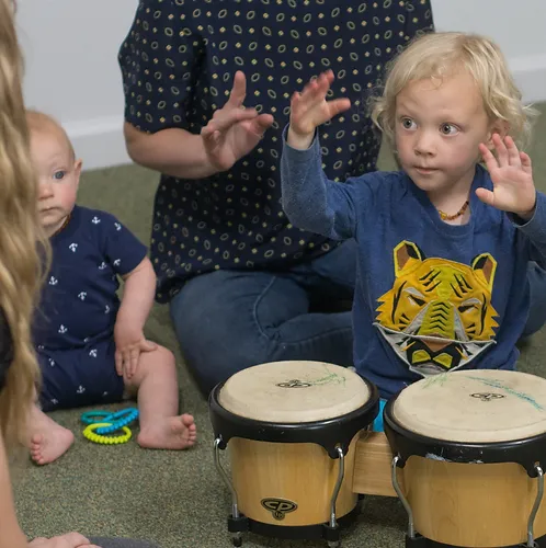 Toddlers and parent playing bongo drums in music class