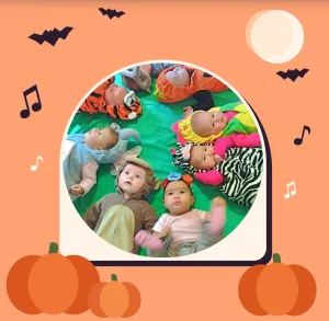 Babies in Halloween costumes lying in a circle on a green mat