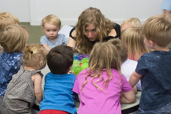 Kids playing a giant drum together during Toe Tappin Toddlers group music class.